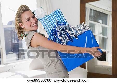 Portrait of a young woman holding a stack of gifts and smiling View Large Photo Image Stock Image - Portrait of a young woman holding a stack of gifts and smiling. Fotosearch