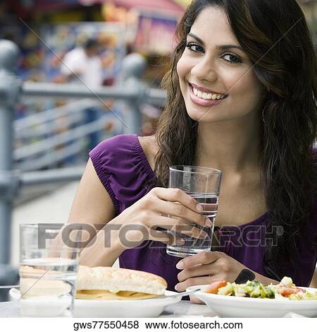 Stock Photo - Portrait of a young woman holding a glass of water and smiling. Fotosearch