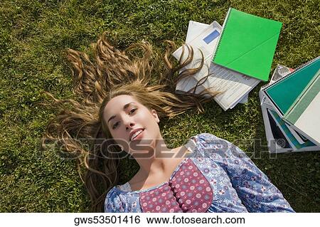 Portrait of a young woman lying on grass View Large Photo Image Stock Photograph - Portrait of a young woman lying on grass. Fotosearch