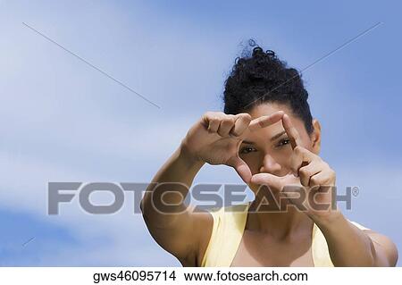 Portrait of a young woman making a finger frame in front of her face View Large Photo Image Picture - Portrait of a young woman making a finger frame in front of her face. Fotosearch