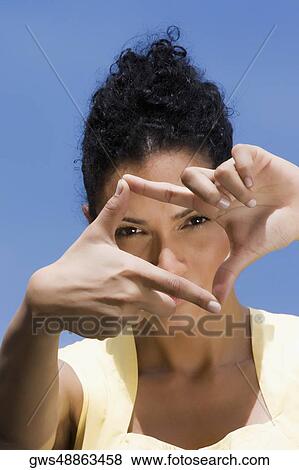 Stock Photo - Portrait of a young woman making a finger frame in front of her face. Fotosearch