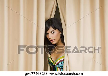 Portrait of a young woman peeking through a curtain View Large Photo Image Stock Photo - Portrait of a young woman peeking through a curtain. Fotosearch