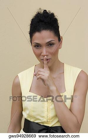 Portrait of a young woman putting her finger on her lips View Large Photo Image Stock Photo - Portrait of a young woman putting her finger on her lips. Fotosearch