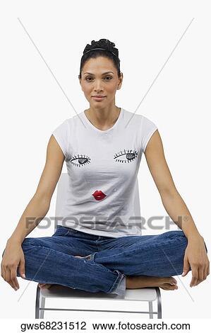 Portrait of a young woman sitting on a chair with her legs crossed View Large Photo Image Stock Image - Portrait of a young woman sitting on a chair with her legs crossed. Fotosearch