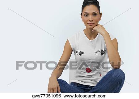 Portrait of a young woman sitting on a chair with her legs crossed View Large Photo Image Stock Photograph - Portrait of a young woman sitting on a chair with her legs crossed. Fotosearch