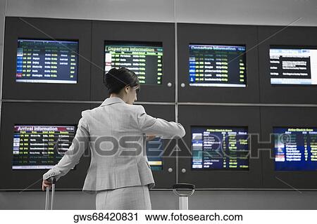 Rear view of a businesswoman checking the time at an airport View Large Photo Image Stock Image - Rear view of a businesswoman checking the time at an airport. Fotosearch