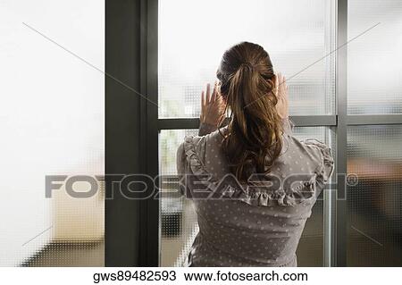 Rear view of a businesswoman looking through a window View Large Photo Image Stock Image - Rear view of a businesswoman looking through a window. Fotosearch
