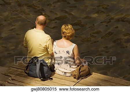 Rear view of a couple sitting on a boardwalk, Bay of Naples, Sorrento, Sorrentine Peninsula, Naples Province, Campania, Italy View Large Photo Image Stock Photography - Rear view of a couple sitting on a boardwalk, Bay of Naples, Sorrento, Sorrentine Peninsula, Naples Province, Campania, Italy. Fotosearch