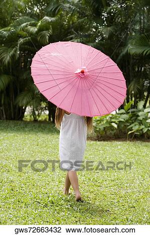 Rear view of a girl holding a parasol and walking in a park View Large Photo Image Stock Image - Rear view of a girl holding a parasol and walking in a park. Fotosearch