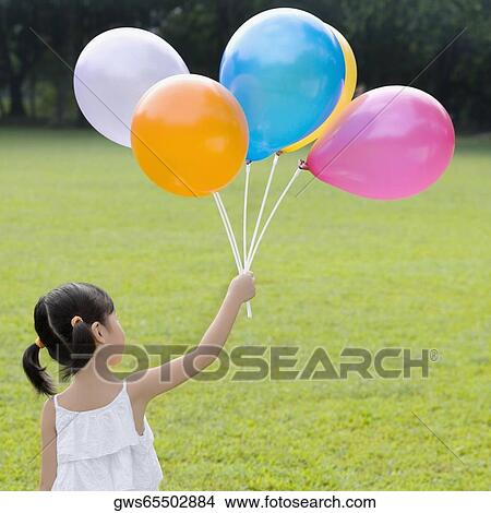 Rear view of a girl holding balloons in a park View Large Photo Image Picture - Rear view of a girl holding balloons in a park. Fotosearch