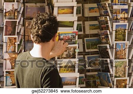 Rear view of a man choosing postcards, Piazza Della Cisterna, San Gimignano, Siena Province, Tuscany, Italy View Large Photo Image Stock Photography - Rear view of a man choosing postcards, Piazza Della Cisterna, San Gimignano, Siena Province, Tuscany, Italy. Fotosearch
