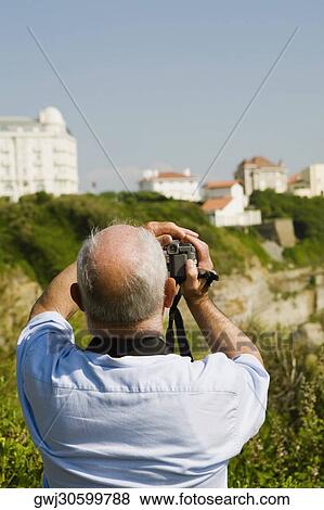 Rear view of a man filming with his home video camera, Biarritz, Basque Country, Pyrenees-Atlantiques, Aquitaine, France View Large Photo Image Stock Photo - Rear view of a man filming with his home video camera, Biarritz, Basque Country, Pyrenees-Atlantiques, Aquitaine, France. Fotosearch