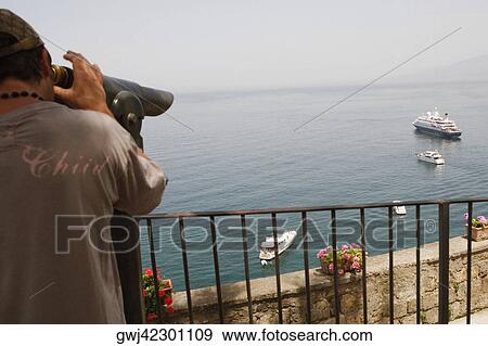 Rear view of a man looking through a coin-operated binocular, Bay of Naples, Via Aniello Califano, Sorrento, Sorrentine Peninsula, Naples Province, Campania, Italy View Large Photo Image Stock Photo - Rear view of a man looking through a coin-operated binocular, Bay of Naples, Via Aniello Califano, Sorrento, Sorrentine Peninsula, Naples Province, Campania, Italy. Fotosearch