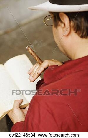 Rear view of a man reading a book and holding a cigar, Piazza Colombo, Mercato Orientale, Genoa, Italy View Large Photo Image Picture - Rear view of a man reading a book and holding a cigar, Piazza Colombo, Mercato Orientale, Genoa, Italy. Fotosearch