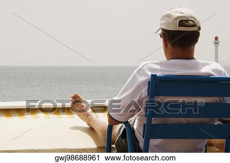 Rear view of a man sitting in an armchair on the beach, Baie De Cannes, Provence-Alpes-Cote D'Azur, France View Large Photo Image Stock Image - Rear view of a man sitting in an armchair on the beach, Baie De Cannes, Provence-Alpes-Cote D'Azur, France. Fotosearch