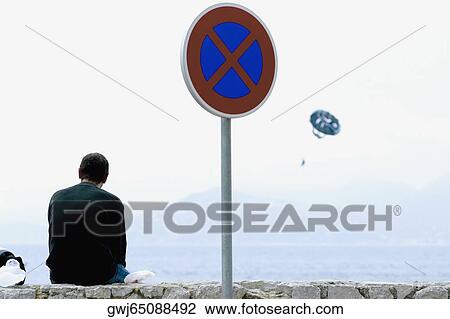 Rear view of a man sitting on a stone wall at the seaside, Baie De Cannes, Cote d'Azur, Cannes, Provence-Alpes-Cote D'Azur, France View Large Photo Image Stock Image - Rear view of a man sitting on a stone wall at the seaside, Baie De Cannes, Cote d'Azur, Cannes, Provence-Alpes-Cote D'Azur, France. Fotosearch