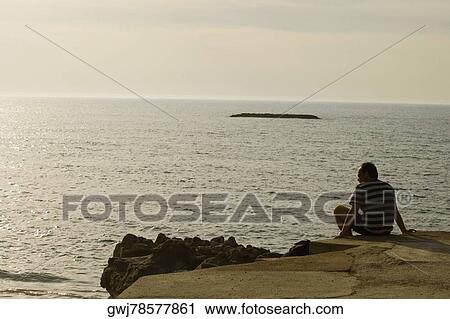 Rear view of a man sitting on the oceanside, Biarritz, France View Large Photo Image Stock Image - Rear view of a man sitting on the oceanside, Biarritz, France. Fotosearch