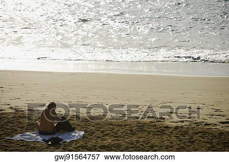 Rear view of a man sitting on the beach, Grande Plage, Biarritz, France View Large Photo Image Stock Photo - Rear view of a man sitting on the beach, Grande Plage, Biarritz, France. Fotosearch