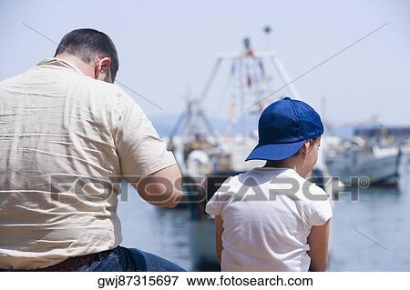 Rear view of a man with a boy sitting at the seaside, Italian Riviera, Santa Margherita Ligure, Genoa, Liguria, Italy View Large Photo Image Stock Photo - Rear view of a man with a boy sitting at the seaside, Italian Riviera, Santa Margherita Ligure, Genoa, Liguria, Italy. Fotosearch