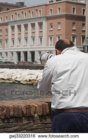 Rear view of a man with a hand-held telescope, Via Partenope, Bay of Naples, Naples, Naples Province, Campania, Italy View Large Photo Image Stock Photograph - Rear view of a man with a hand-held telescope, Via Partenope, Bay of Naples, Naples, Naples Province, Campania, Italy. Fotosearch