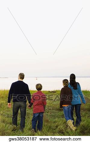 Rear view of a mid adult couple with their two children walking together View Large Photo Image Stock Photo - Rear view of a mid adult couple with their two children walking together. Fotosearch