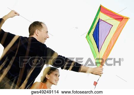 Rear view of a mid adult man with his daughter flying a kite View Large Photo Image Picture - Rear view of a mid adult man with his daughter flying a kite. Fotosearch