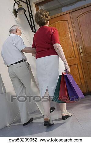 Rear view of a senior couple walking with shopping bags View Large Photo Image Stock Image - Rear view of a senior couple walking with shopping bags. Fotosearch