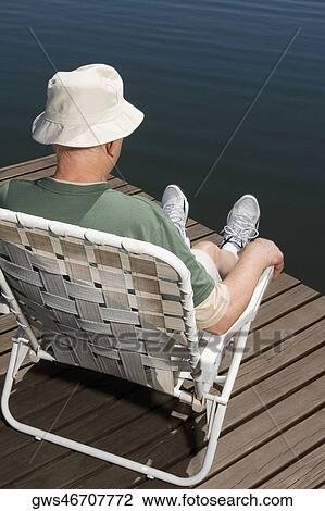 Rear view of a senior man sitting on a chair at the lakeside View Large Photo Image Stock Image - Rear view of a senior man sitting on a chair at the lakeside. Fotosearch