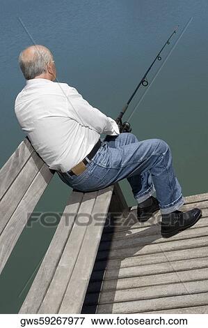 Rear view of a senior man sitting on a bench at the lakeside and fishing View Large Photo Image Stock Photo - Rear view of a senior man sitting on a bench at the lakeside and fishing. Fotosearch