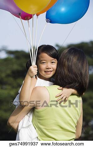 Rear view of a woman carrying her daughter View Large Photo Image Stock Photo - Rear view of a woman carrying her daughter. Fotosearch