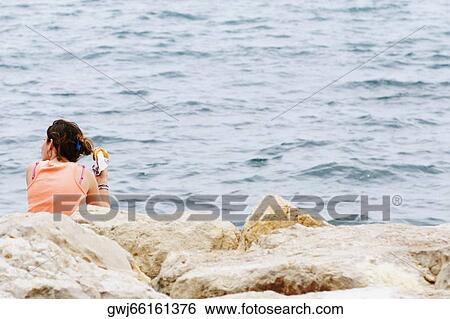 Rear view of a woman sitting at the seaside, Baie De Cannes, Cote d'Azur, Cannes, Provence-Alpes-Cote D'Azur, France View Large Photo Image Stock Photograph - Rear view of a woman sitting at the seaside, Baie De Cannes, Cote d'Azur, Cannes, Provence-Alpes-Cote D'Azur, France. Fotosearch