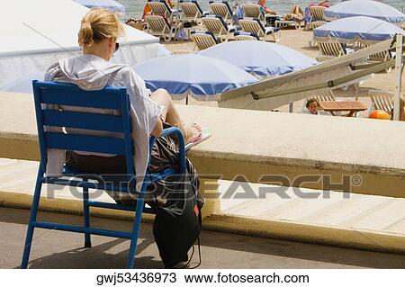 Rear view of a woman sitting in an armchair on the beach, Plage De La Croisette, Cote d'Azur, Cannes, Provence-Alpes-Cote D'Azur, France View Large Photo Image Stock Image - Rear view of a woman sitting in an armchair on the beach, Plage De La Croisette, Cote d'Azur, Cannes, Provence-Alpes-Cote D'Azur, France. Fotosearch