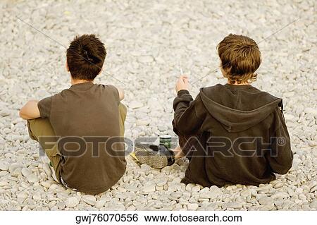 Stock Photograph - Rear view of a woman smoking with a man sitting beside her, Nice, Provence-Alpes-Cote D'Azur, France. Fotosearch