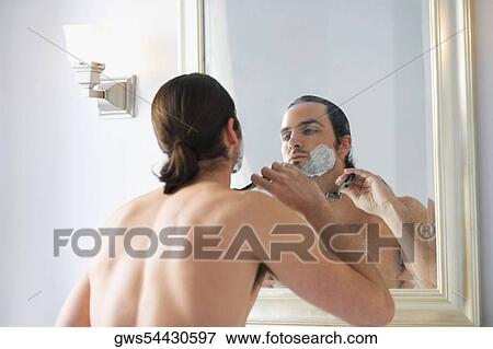 Rear view of a young man shaving his face View Large Photo Image Stock Photo - Rear view of a young man shaving his face. Fotosearch