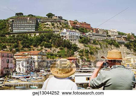 Rear view of tourists photographing a harbor, Marina Grande, Capri, Sorrento, Sorrentine Peninsula, Naples Province, Campania, Italy View Large Photo Image Stock Image - Rear view of tourists photographing a harbor, Marina Grande, Capri, Sorrento, Sorrentine Peninsula, Naples Province, Campania, Italy. Fotosearch