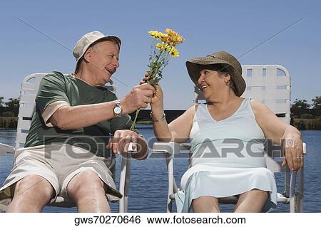 Stock Photograph - Senior man giving a bunch of flowers to a senior woman. Fotosearch