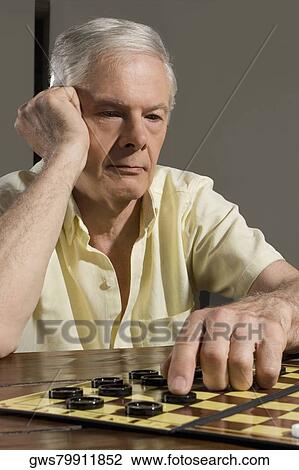 Stock Image - Senior man playing checkers. Fotosearch