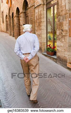 Senior man walking in a street, San Gimignano, Siena Province, Tuscany, Italy View Large Photo Image Stock Photo - Senior man walking in a street, San Gimignano, Siena Province, Tuscany, Italy. Fotosearch