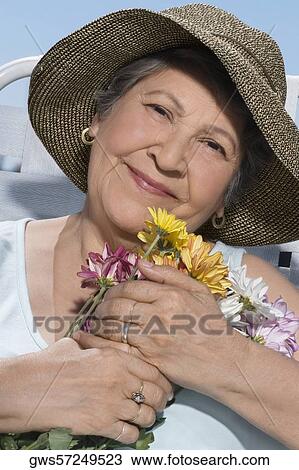Stock Image - Senior woman holding bunch of flowers. Fotosearch