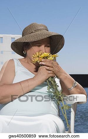 Stock Photo - Senior woman smelling flowers. Fotosearch