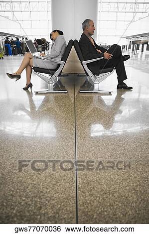 Side profile of a businessman and a businesswoman sitting at an airport lounge View Large Photo Image Stock Photograph - Side profile of a businessman and a businesswoman sitting at an airport lounge. Fotosearch