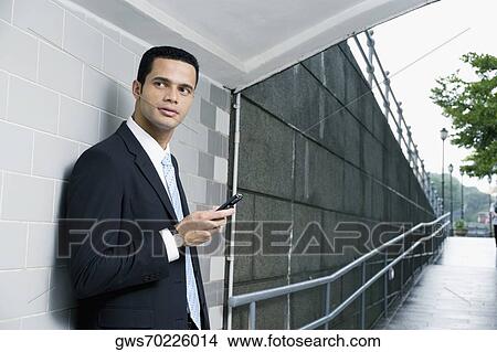 Side profile of a businessman holding a mobile phone in a subway View Large Photo Image Picture - Side profile of a businessman holding a mobile phone in a subway. Fotosearch