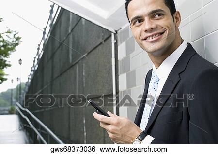 Side profile of a businessman holding a mobile phone in a subway View Large Photo Image Stock Photograph - Side profile of a businessman holding a mobile phone in a subway. Fotosearch