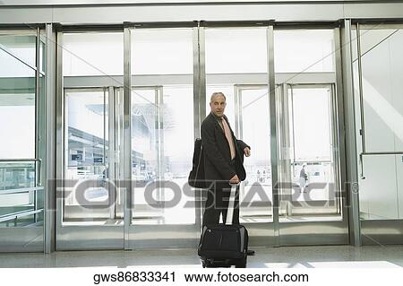 Side profile of a businessman pulling his luggage at an airport View Large Photo Image Stock Image - Side profile of a businessman pulling his luggage at an airport. Fotosearch