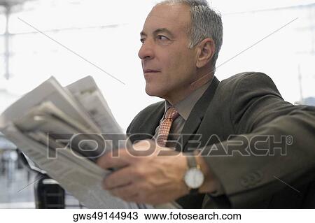 Side profile of a businessman sitting at an airport and holding a newspaper View Large Photo Image Stock Image - Side profile of a businessman sitting at an airport and holding a newspaper. Fotosearch