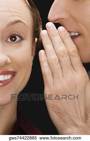 Stock Photography - Side profile of a businessman whispering to a businesswoman. Fotosearch