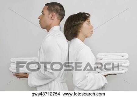 Picture - Side profile of a mid adult man with a young woman holding stacks of towels. Fotosearch