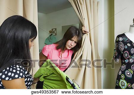 Stock Photo - Side profile of a sales clerk giving a dress to a young woman. Fotosearch