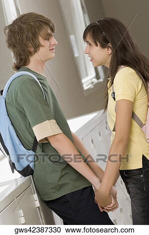 Side profile of a teenage couple holding hands and looking at each other View Large Photo Image Stock Image - Side profile of a teenage couple holding hands and looking at each other. Fotosearch