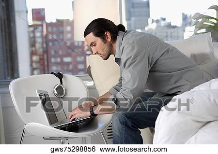 Side profile of a young man using a laptop View Large Photo Image Stock Photograph - Side profile of a young man using a laptop. Fotosearch